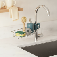 Close-up of a slate blue sink caddy organizer on a bright white kitchen counter, holding a sponge, dish brush, scrubber, and 